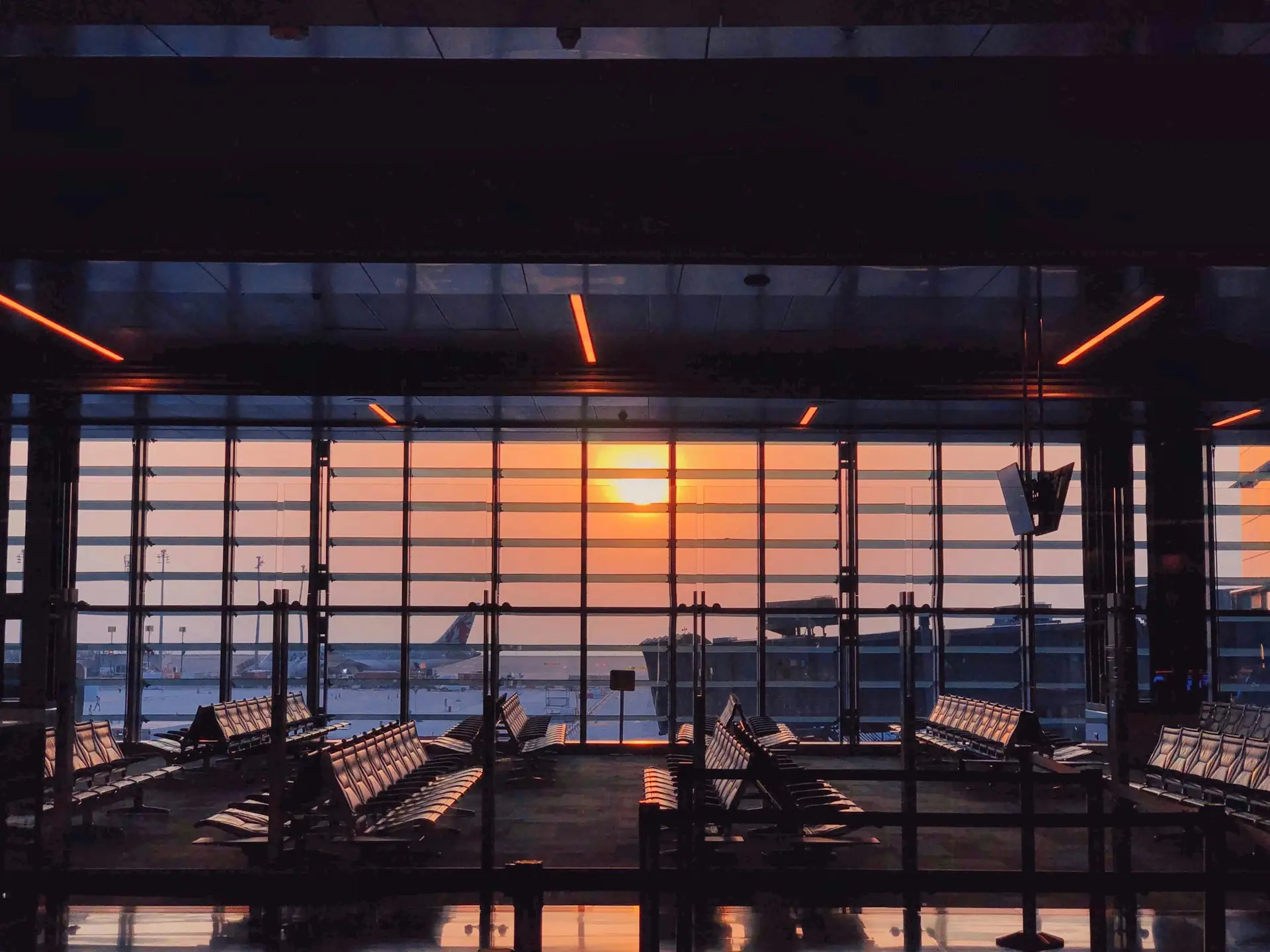 Airport departure lounge facing the runway at sunset
