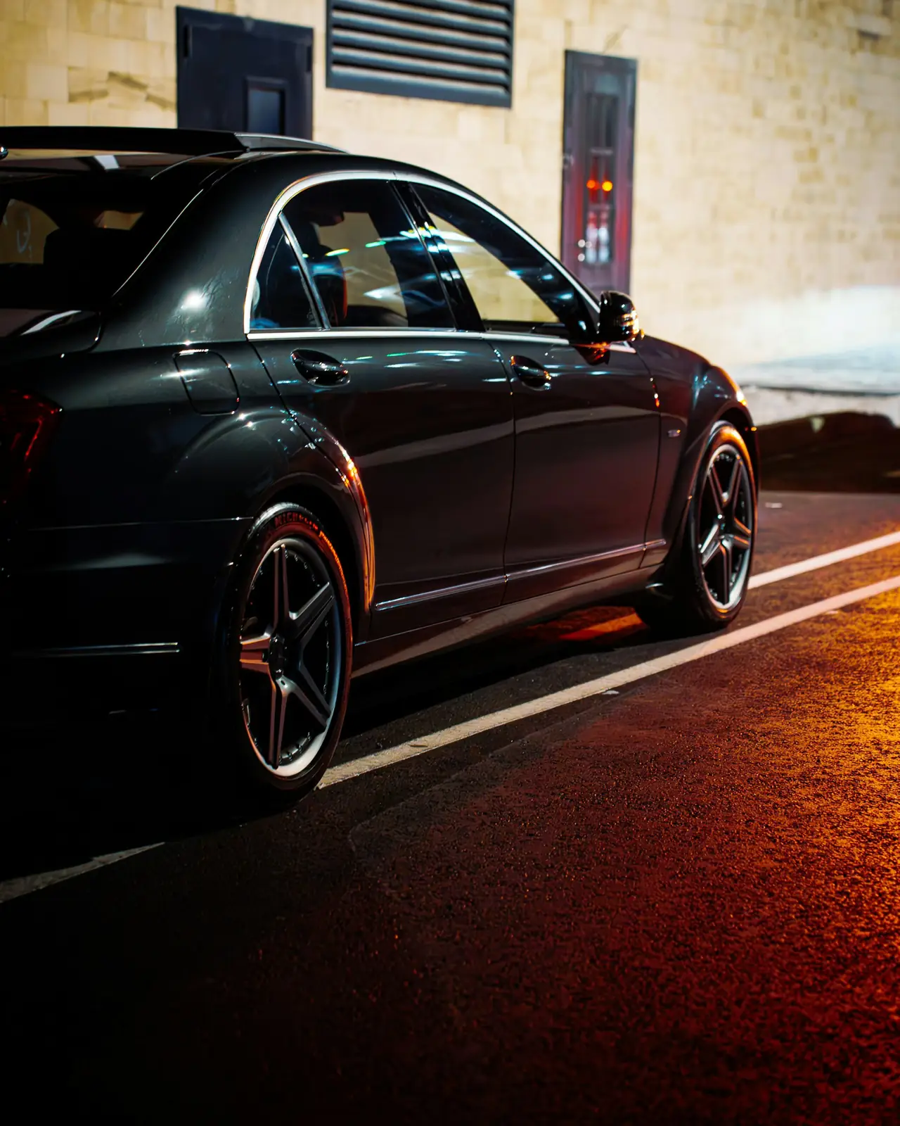 Black luxury sedan parked on a city street at dusk