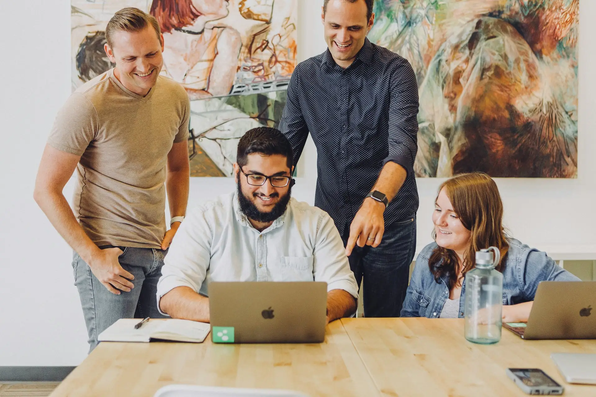 Small team gathered around a laptop in a creative office